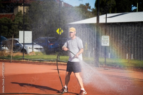 friends playing tennis on a clay court, watering and bagging a clay court. doing tennis court maintenance