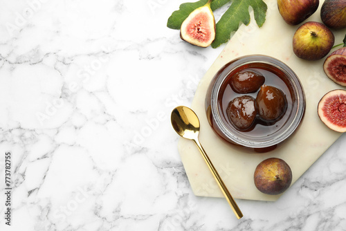 Jar of tasty sweet jam and fresh figs on white marble table, flat lay. Space for text photo