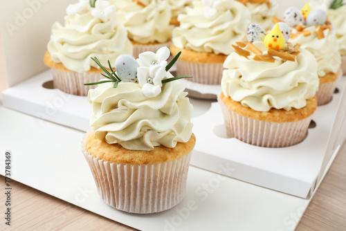 Tasty Easter cupcakes in box on wooden table, closeup