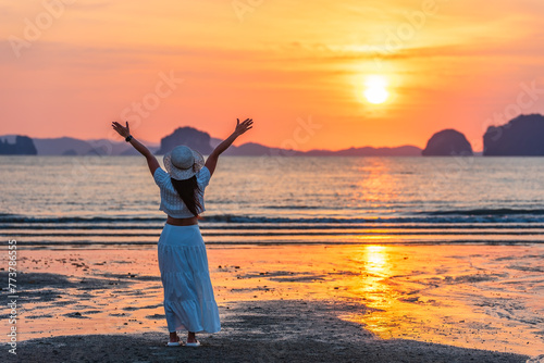 Happy woman traveler, arms rised, enjoying sunset at sea, Phuket and Krabi travel sounthern Thailand. photo