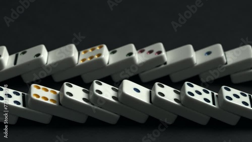 spaced line of white dominoes topples sequentially from left to right across a smooth