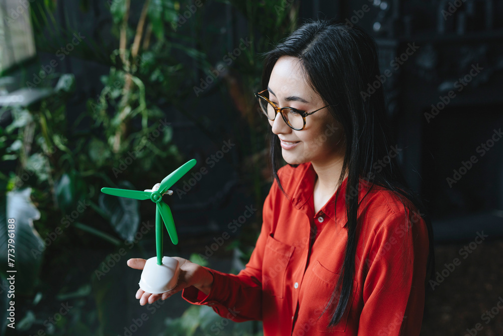 Smiling businesswoman with wind turbine model Smiling businesswoman with wind turbine model