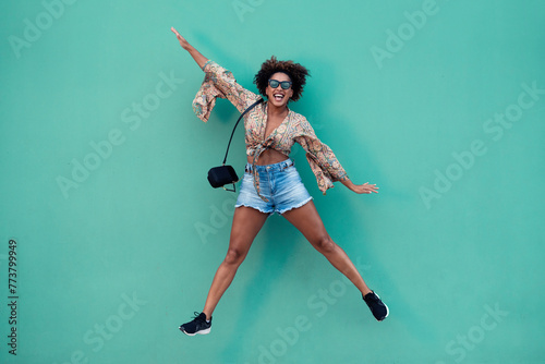 Cheerful woman jumping against green background photo