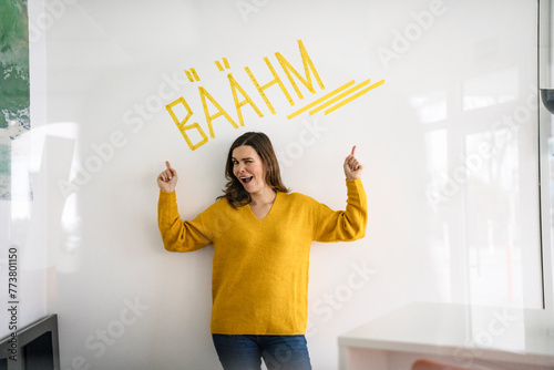 Creative businesswoman pointing at text in front of white wall with text in office