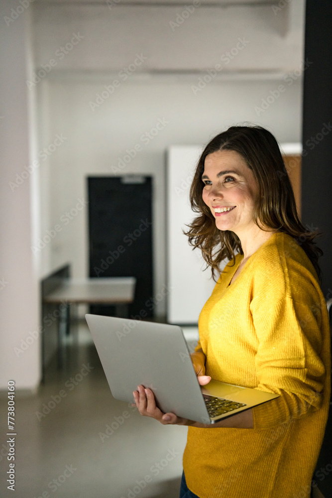 Smiling creative businesswoman with laptop in office Smiling creative businesswoman with laptop in office