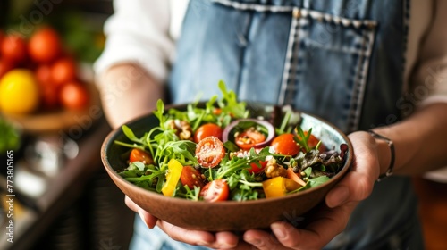Chef in striped apron presenting a handcrafted salad bowl filled with vibrant greens and vegetables.