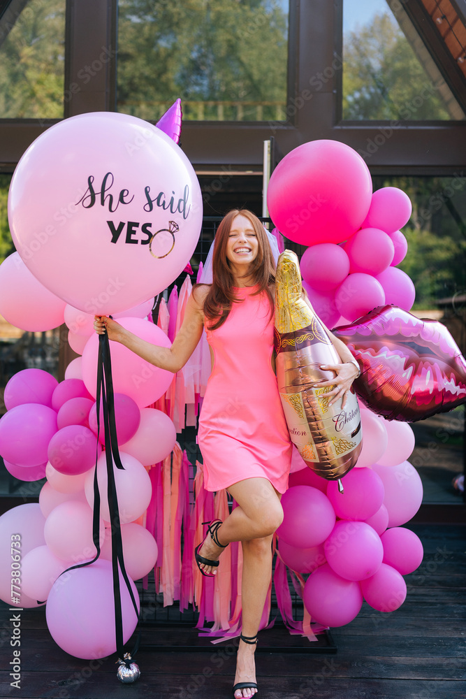 Vertical portrait of loving redhead bride in summer wedding dress posing holding various colorful festive foil helium balloons standing by country house, closed eyes with happy expression. - obrazy, fototapety, plakaty 