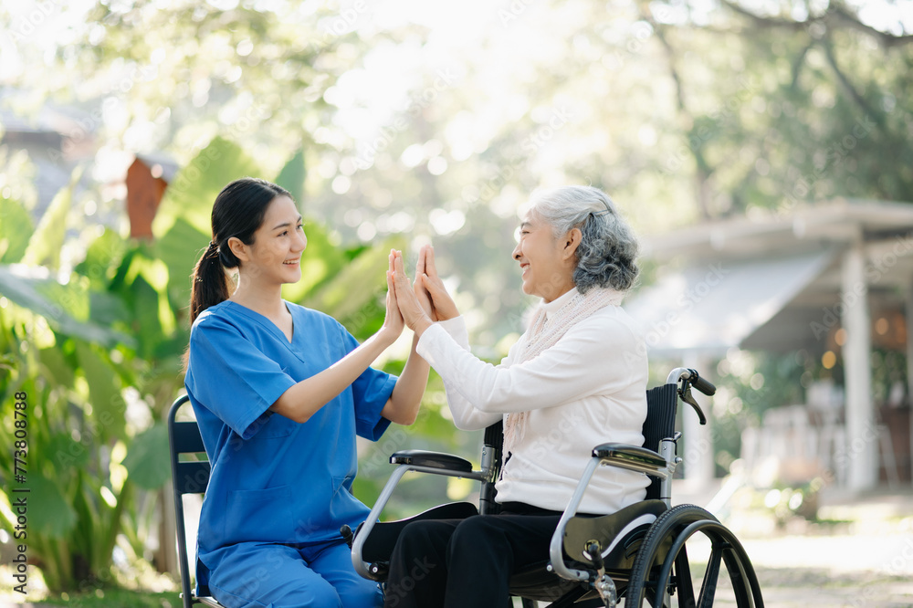 Elderly asian senior woman on wheelchair with Asian careful caregiver and encourage patient, walking in garden. with care from a caregiver Elderly asian senior woman on wheelchair with Asian careful caregiver and encourage patient, walking in garden. with care from a caregiver