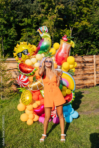 Canvas Print Vertical portrait of elegant blonde female in summer dress and sunglasses holdin