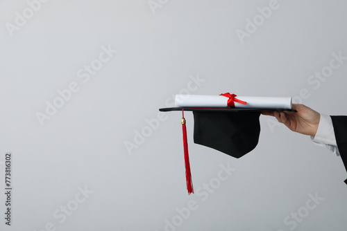 Diploma and hat of a university graduate, on a gray background. © Atlas