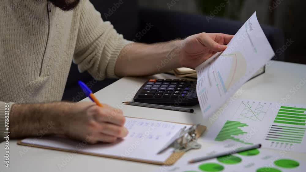Man Analyzing Financial Charts and Calculating Budget in Home Office Setting
