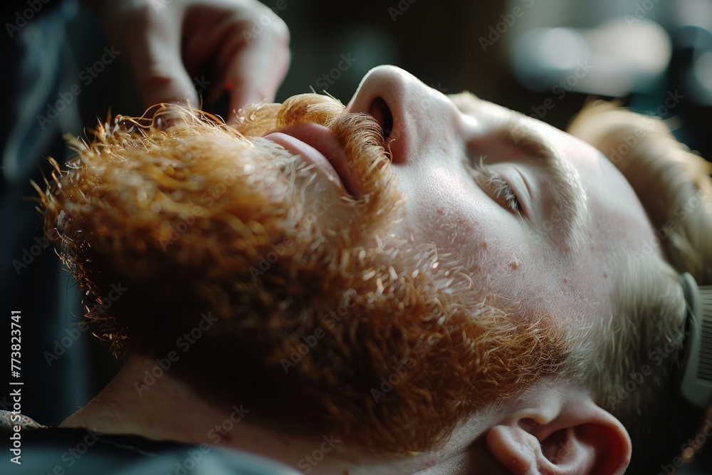 Naklejka premium Man reclining in a chair while receiving a beard trim