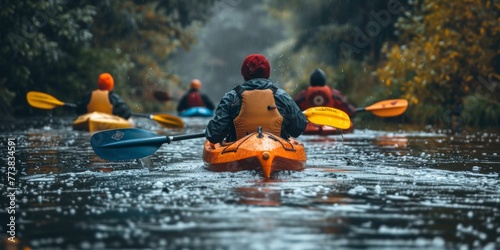 A group of people are pictured paddling down a river in kayaks. This image can be used to depict outdoor recreational activities and team adventures. © Sanych