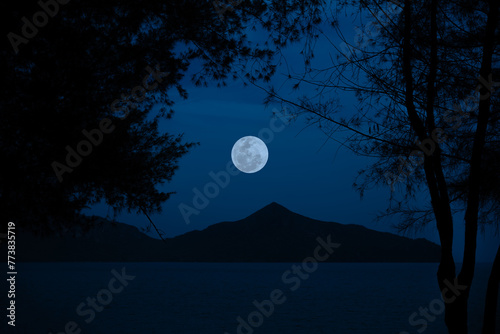 Full moon on sky over sea with mountain in the night.