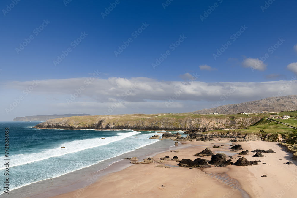 The vast expanse of Durness Beach in Scotland is depicted here, with its azure waters and golden sands strewn with dark rocks, framed by rugged cliffs and a clear, expansive sky