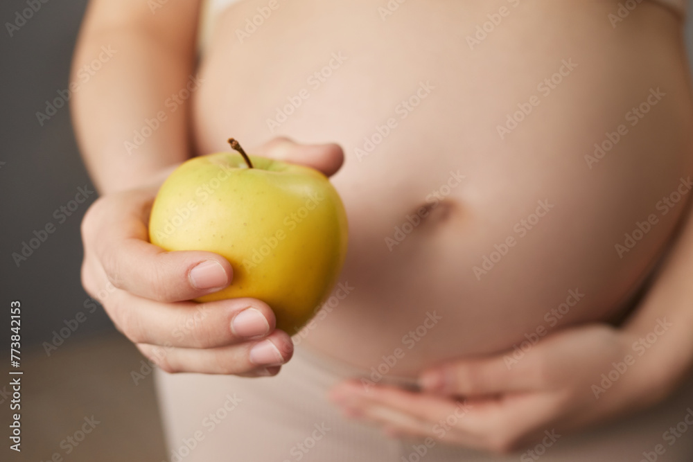 Unknown pregnant woman holding organic yellow apple enjoying healthy nutrition during pregnancy unrecognizable expectant lady having vitamin snack at home Unknown pregnant woman holding organic yellow apple enjoying healthy nutrition during pregnancy unrecognizable expectant lady having vitamin snack at home