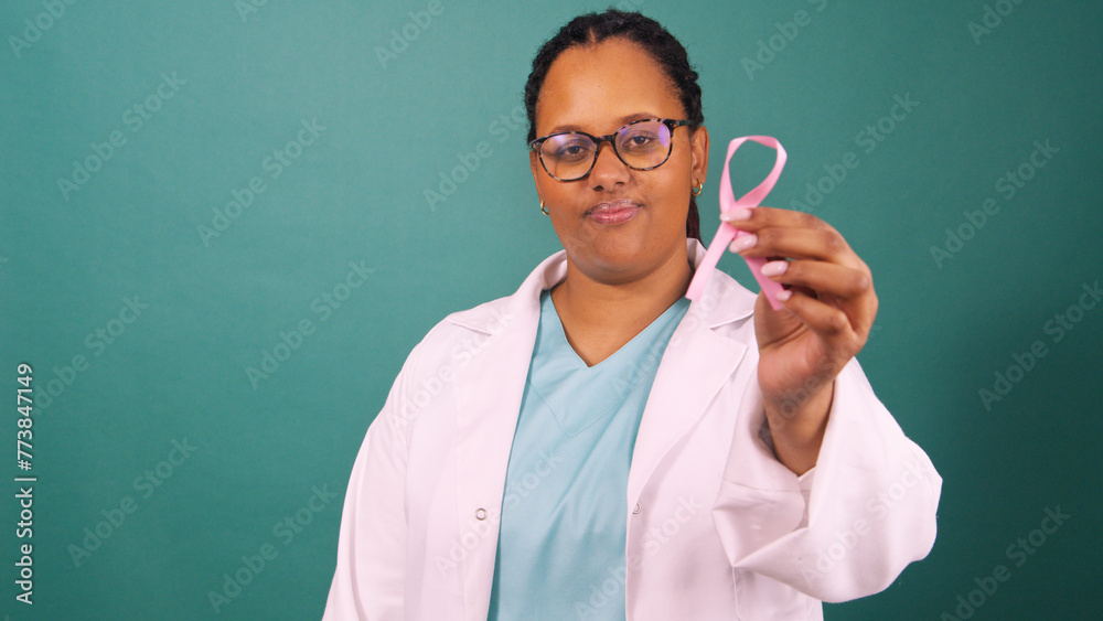 Black female doctor holding pink breast cancer awareness ribbon, serious face