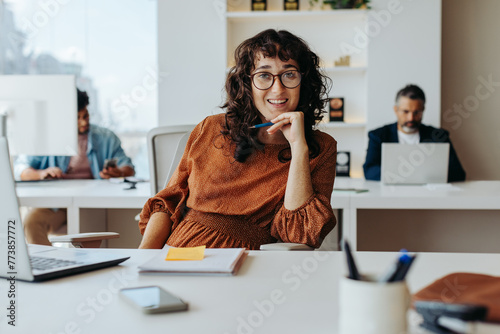Young businesswoman working at her office desk and smiling at the camera