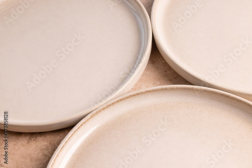Beige ceramic dinner plates on a brown stone tabletop.