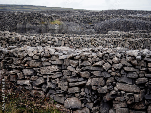 Traditional dry stone fence by a field. Aran islands, county Galway, Ireland. Popular tourist area with stunning nature scenery and endless stone fences. Old craft and simple construction material.