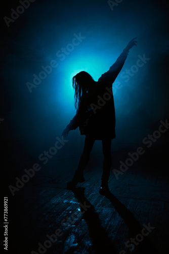cinematic silhouette of a dancing woman with blue lights and fog in the background. 