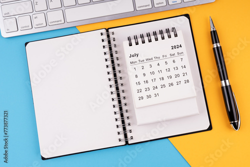 July 2024 calendar, notepad, pen and computer keyboard