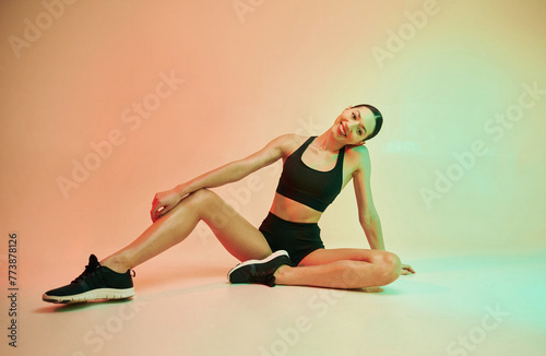 On the floor. Young fitness woman in sportive clothes against background in studio