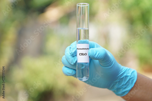 Bilde på lerret Close up hand wear blue glove, holds test tube of Formaldehyde liquid with molecular formula CH2O