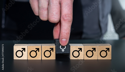 Symbol for choosing a women for a new job. Hand picks wooden cube with a female gender symbol.