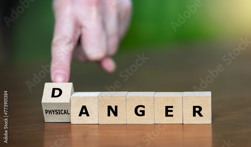 Hand turns wooden cube and changes the expression 'physical anger' to 'danger'.