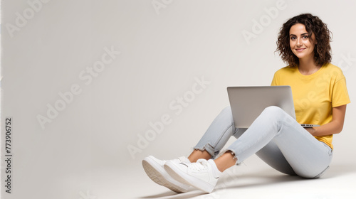 young smiling full-length woman typing on a laptop on a white studio background, copy space
