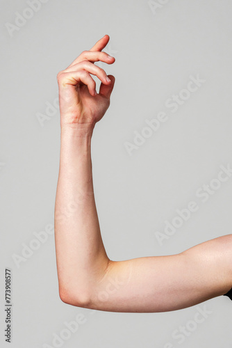 Elevated Bare Human Arm Bent at the Elbow Against a Neutral Background