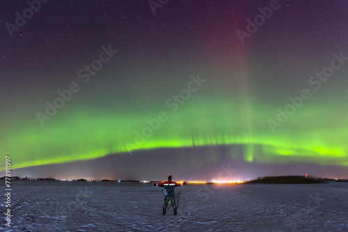 A small figure of a man against the backdrop of the polar lights.