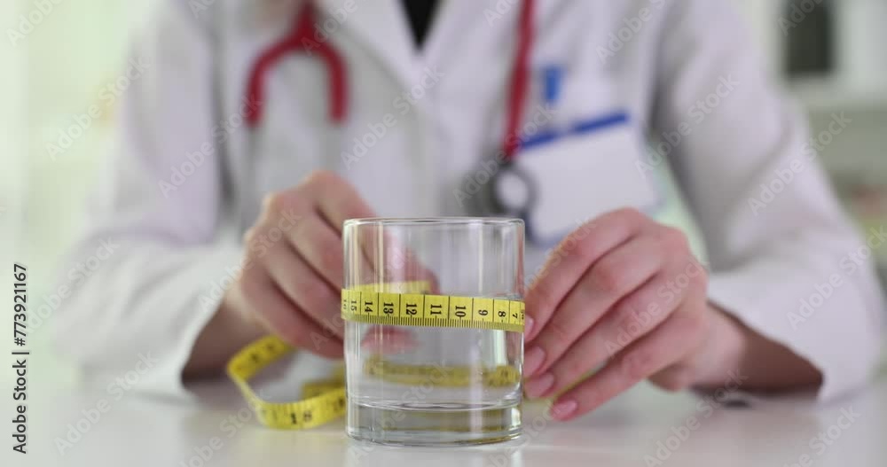Doctor nutritionist measuring glass of water with centimeter tape closeup 4k movie. Proper nutrition and adequate fluid intake concept Doctor nutritionist measuring glass of water with centimeter tape closeup 4k movie. Proper nutrition and adequate fluid intake concept