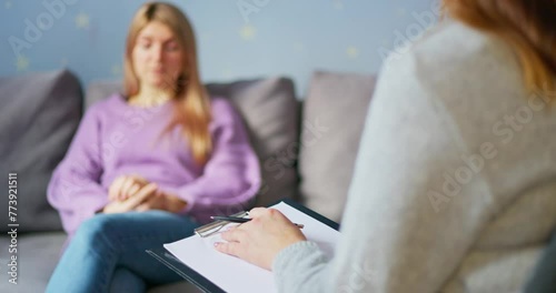 Woman in counseling session with blurred therapist in foreground