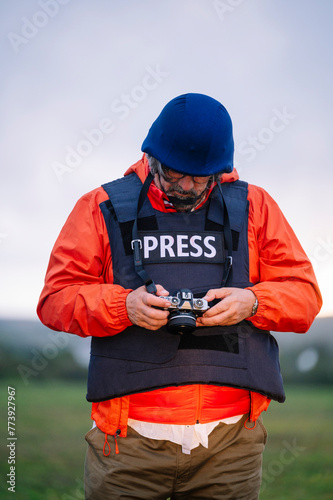 Reporter in bulletproof vest holding a camera.