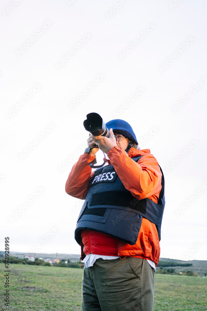 Naklejka premium Reporter in bulletproof vest holding a camera.