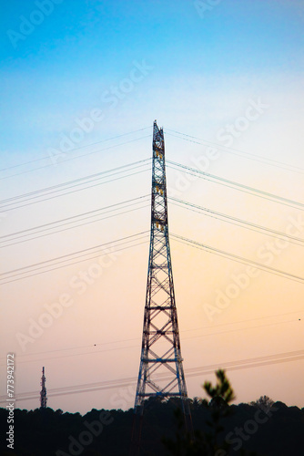 Power lines in front of colorful sky. High voltage line tower. Energy transmission systems. No people. Vertical photo.