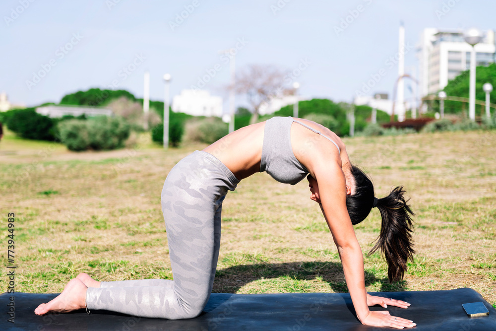 young asian woman doing back stretching exercises with cat pose on her yoga mat, active and healthy lifestyle concept
