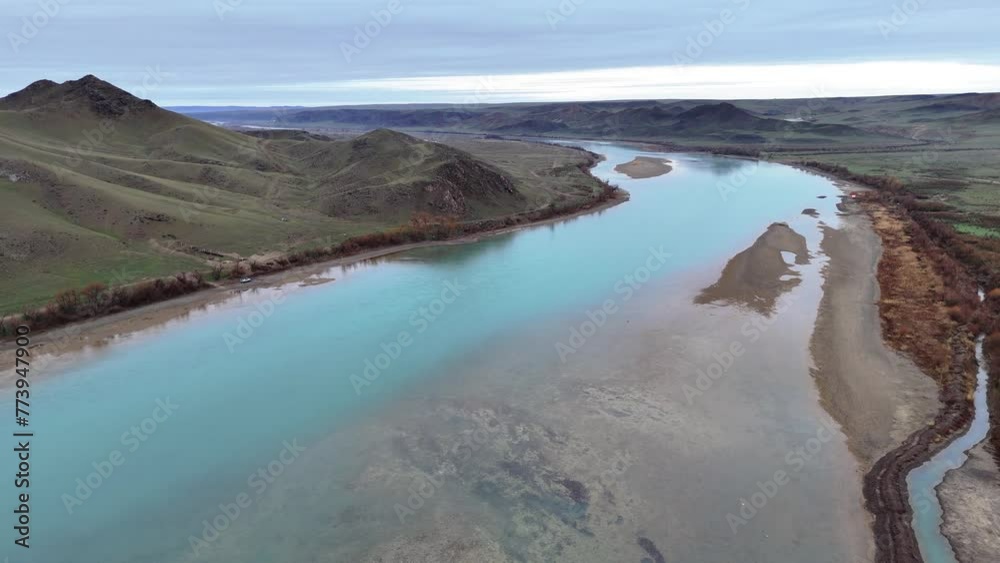 Flying over the river on an overcast spring morning. Shallow river with turquoise water among rocky hills. Ili River, Kazakhstan Flying over the river on an overcast spring morning. Shallow river with turquoise water among rocky hills. Ili River, Kazakhstan