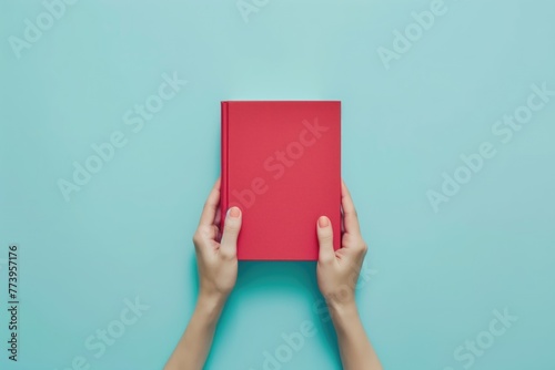 Woman hands holding book with blank red cover over light blue background. Education, back to school, self-learning, book swap, sharing, bookcrossing concept photo