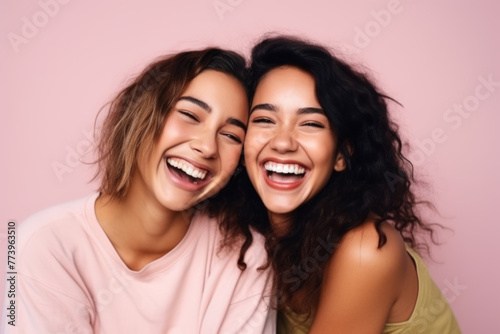 Two Women Laughing Together on Pink Background