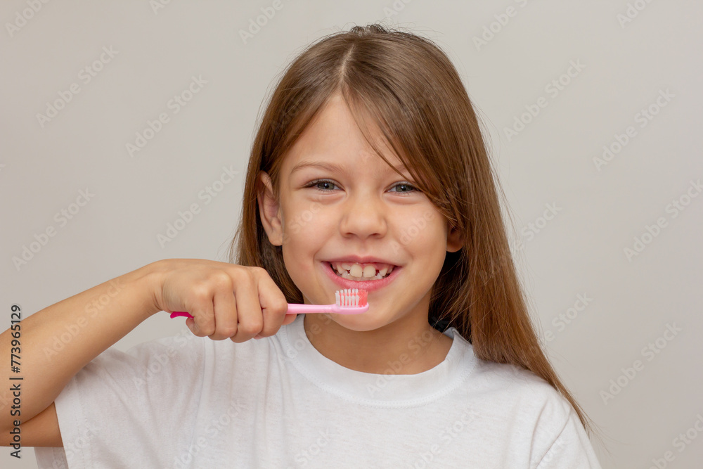 Portrait of caucasian happy little girl with open wide smile holding tooth brush near teeth looking at camera on white background Portrait of caucasian happy little girl with open wide smile holding tooth brush near teeth looking at camera on white background