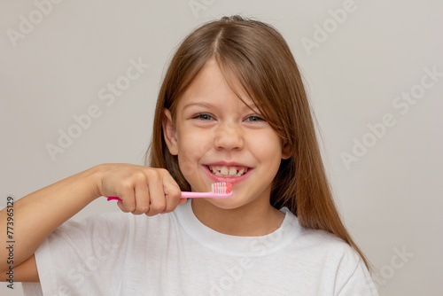 Portrait of caucasian happy little girl with open wide smile holding tooth brush near teeth looking at camera on white background