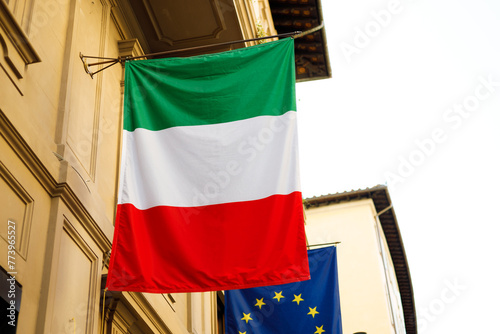 Flag of Italy with EU flag hanging on the wall of a house. Flags in the facade of old building