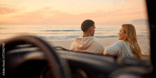 Rear View Of Couple Chatting By Car At Beach Watching Sunrise Together Viewed Through Windshield