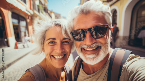 Couple of gray haired mature smiling people travel and taking selfie portrait on phone. Wonderful cheerful man and woman. Active retirees are enjoying life. A man with a gray beard and a woman, travel