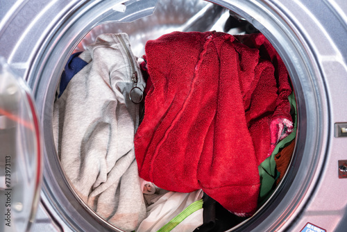 front-loading washing machine filled with clothes and about to start © Freer