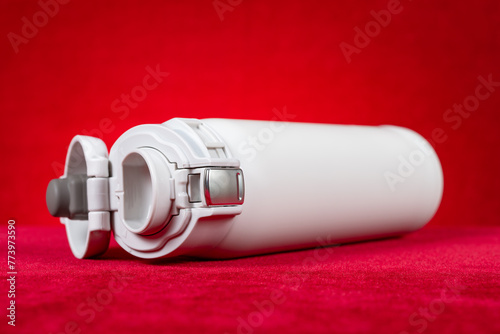 a white vacuum tumbler at horizontal composition on red © Freer