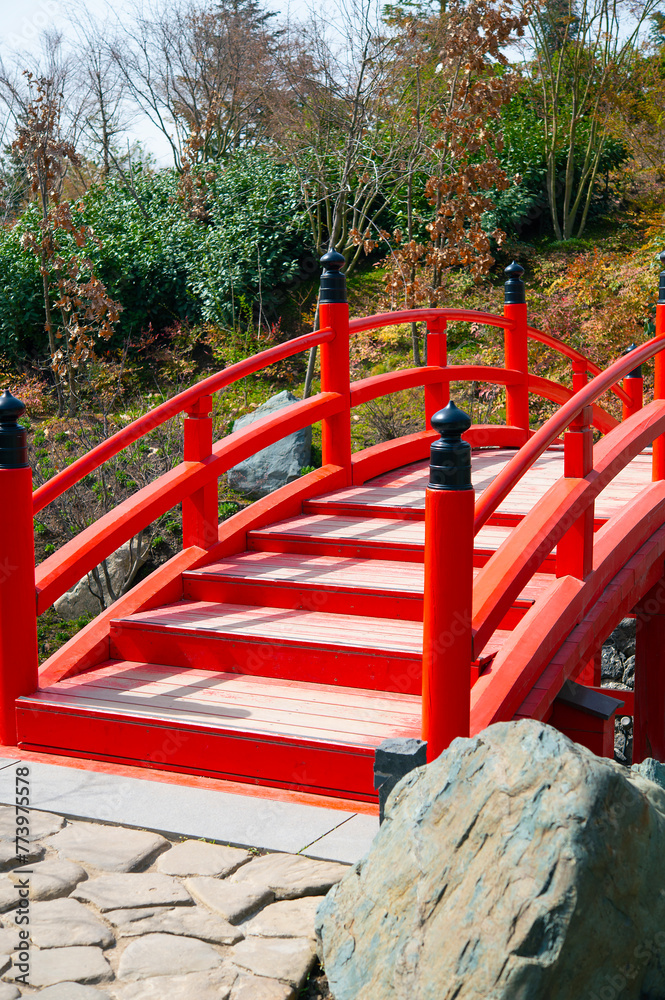 Red wooden bridge in home garden. Decorative element for hiking along a stone path. Red wooden bridge in home garden. Decorative element for hiking along a stone path.